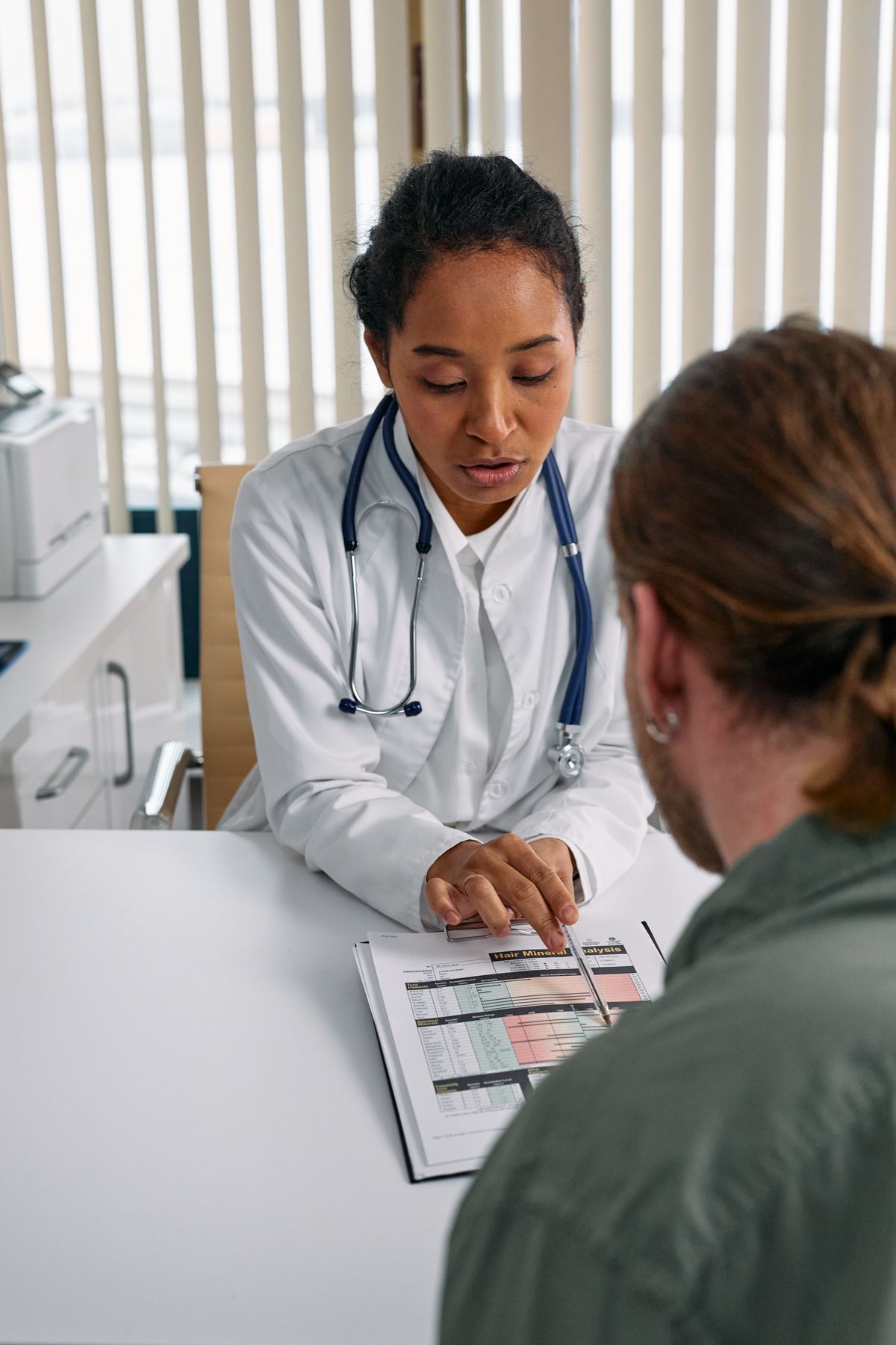 A physician reviewing a health chart carefully during a patient consultation