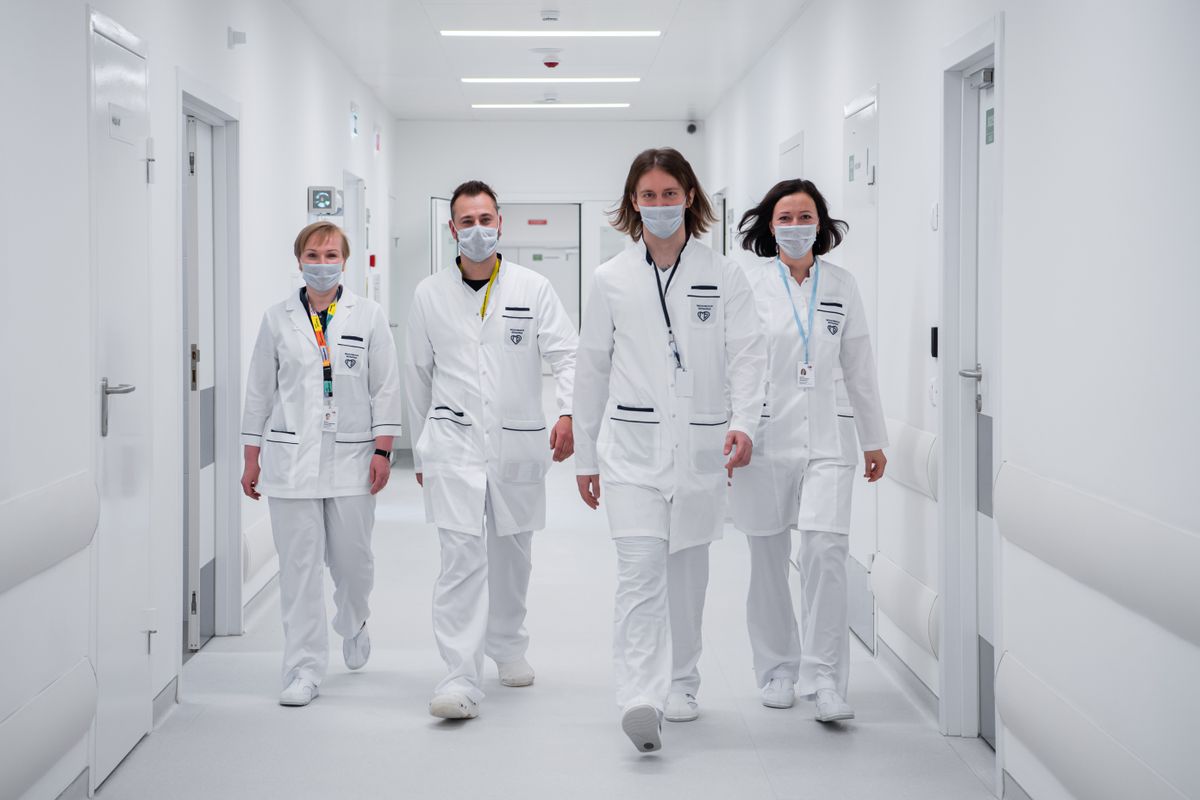 A team of clinicians in white coats walking together through a hospital corridor